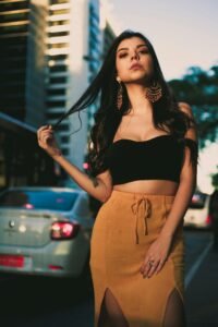 Chic portrait of a young woman in urban setting wearing a crop top and stylish earrings.