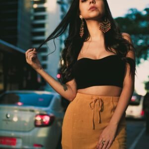 Chic portrait of a young woman in urban setting wearing a crop top and stylish earrings.