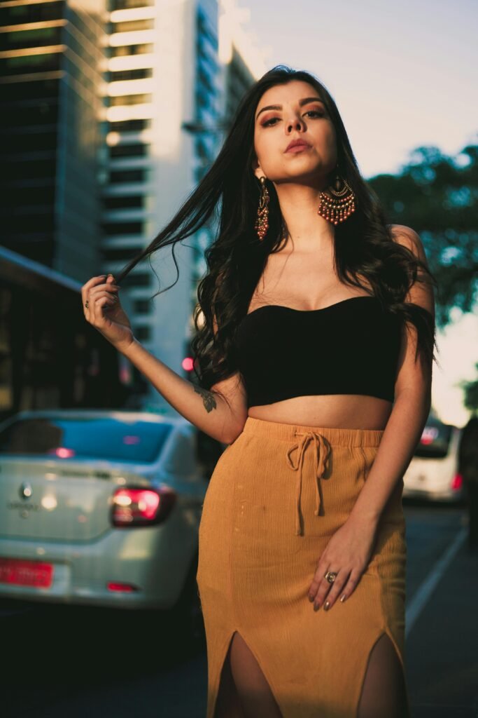 Chic portrait of a young woman in urban setting wearing a crop top and stylish earrings.